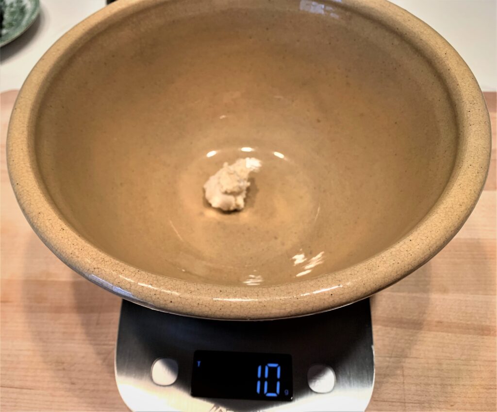 10g of sourdough starter placed in a bowl on top of a digital scale