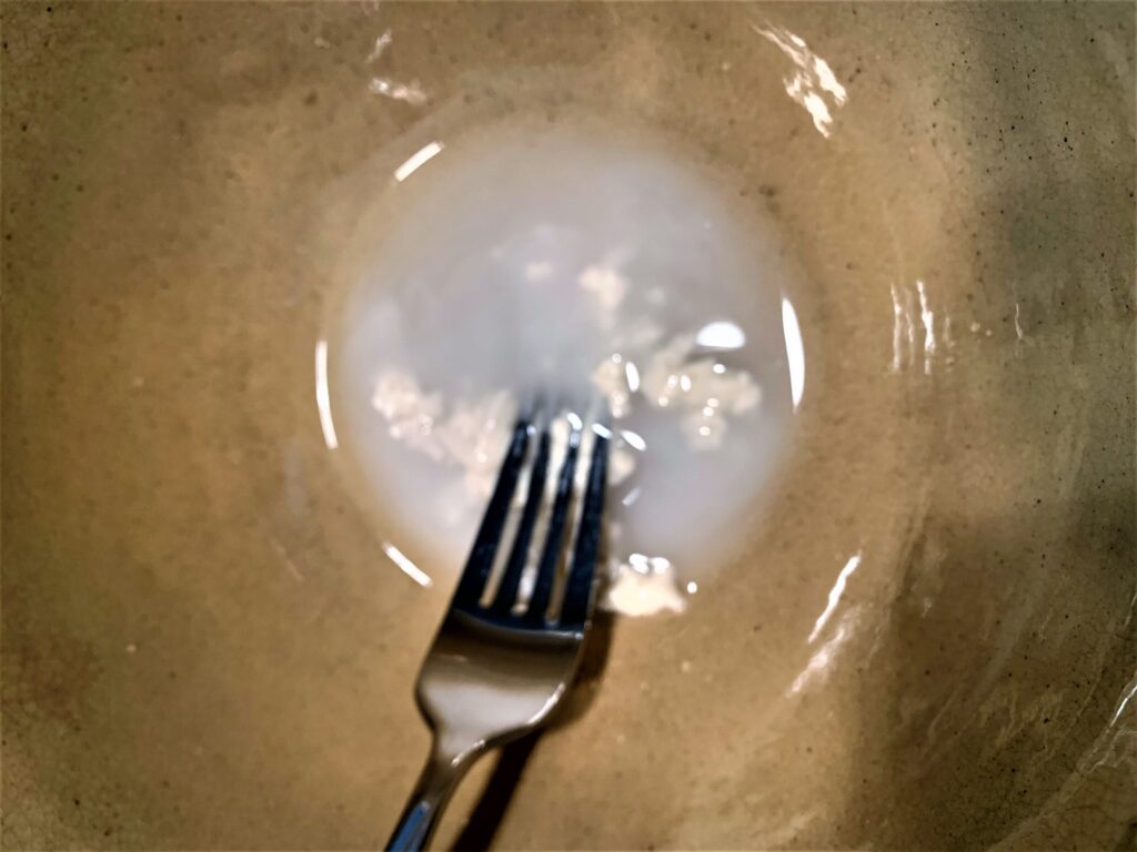 mixing sourdough starter with water using a fork until combined