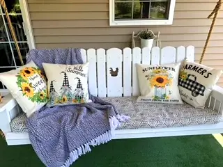 white porch swing with pillows and a blanket