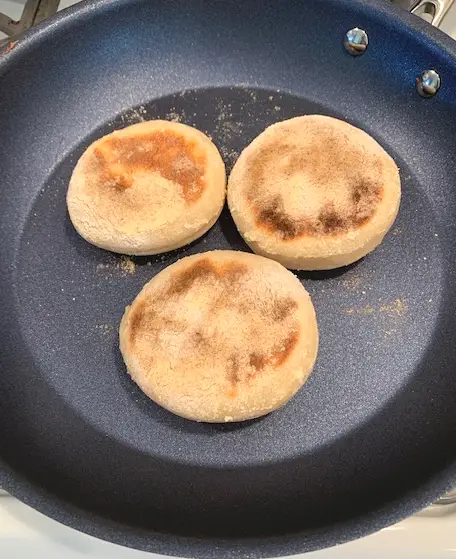 sourdough English muffins turned over in pan to cook on other side