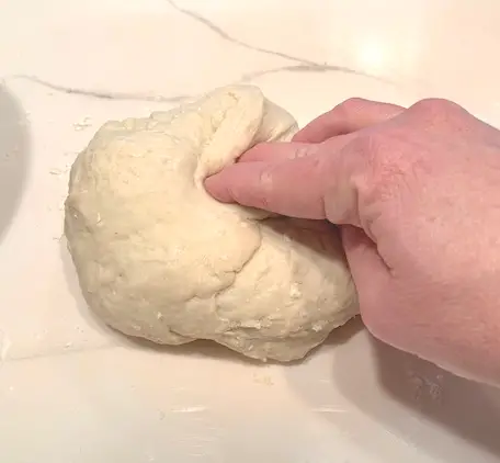 woman pulling dough and folding it into the center