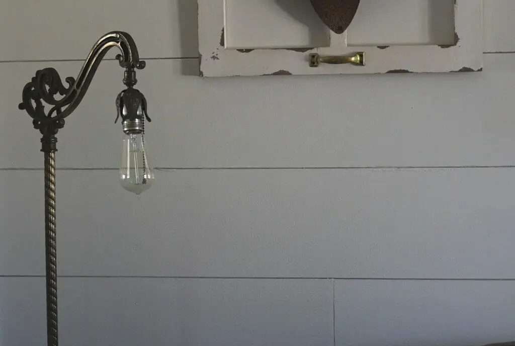 inexpensive farmhouse shiplap made with plywood painted white and antique floor lamp in front