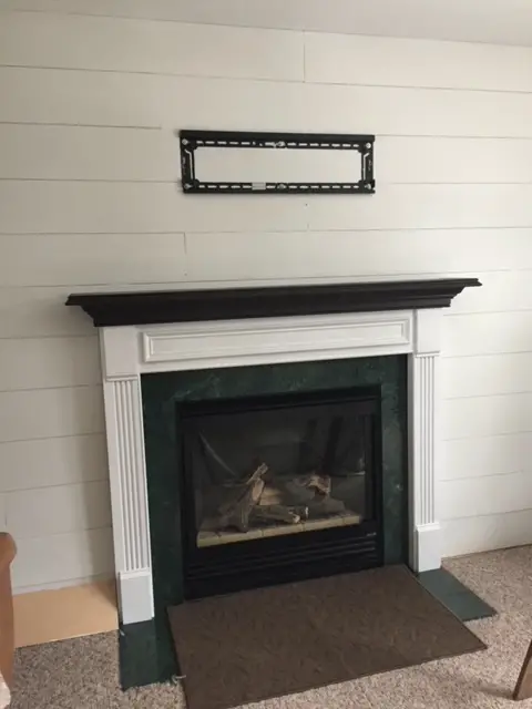 farmhouse shiplap plywood planks painted white with mantel and tv mount on wall