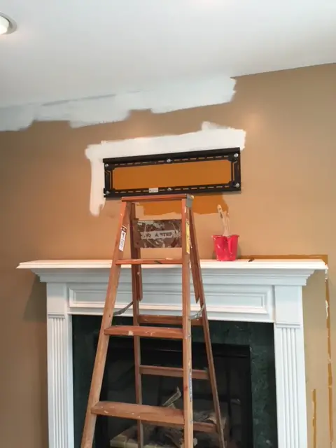 wall with white paint being applied with white mantel and ladder
