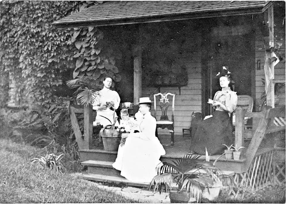three victorian women sitting on a porch having afternoon tea