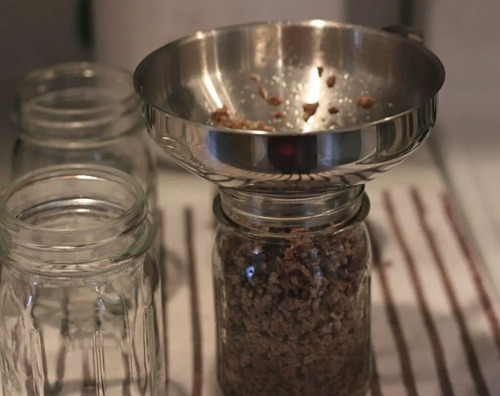funnel in canning jar filled with cooked ground beef