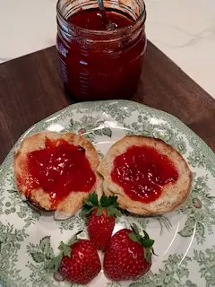 jar of preserved strawberry jam and plate of english muffins with strawberry jam and strawberries