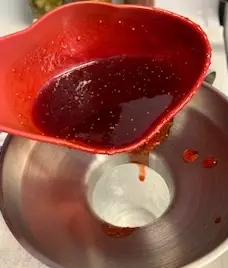 preserved strawberry jam ladled into jar