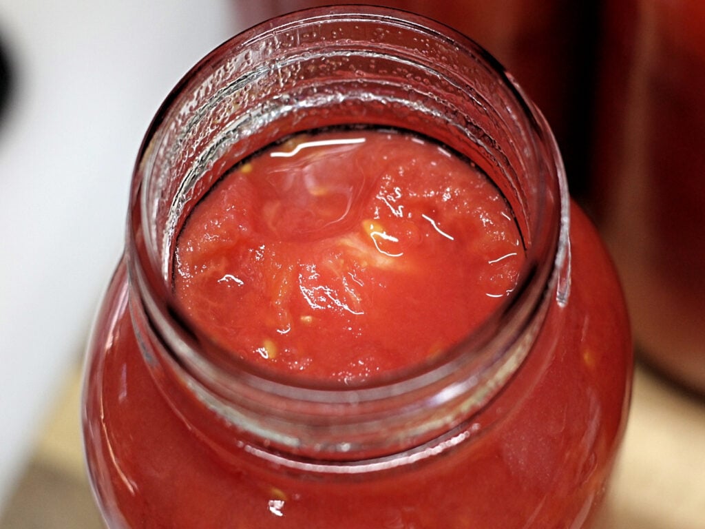 quart jar filled with whole tomatoes and juice