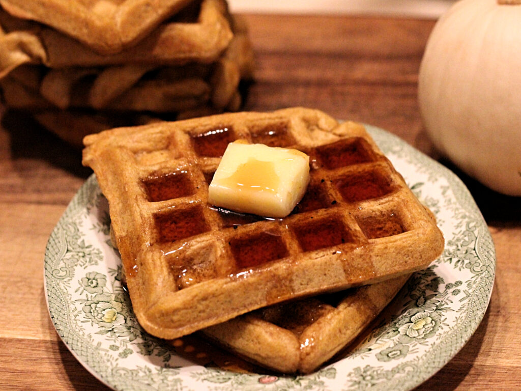 stack of sourdough pumpkin waffles with butter and maple syrup
