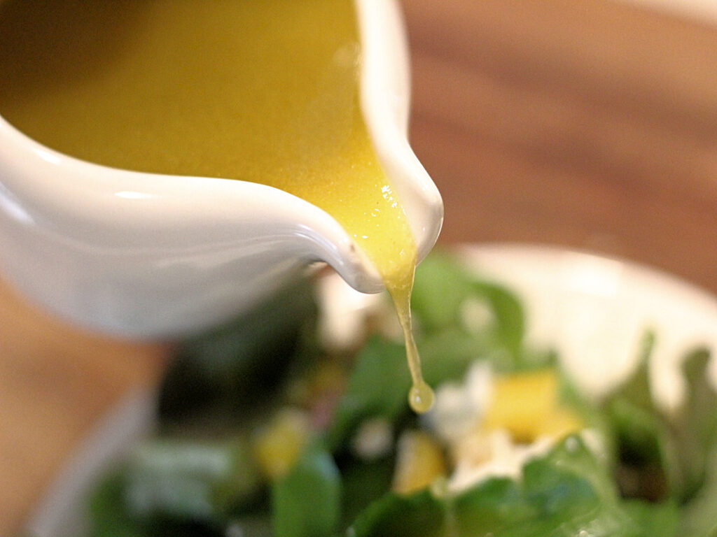 apple cider dressing pouring over a salad