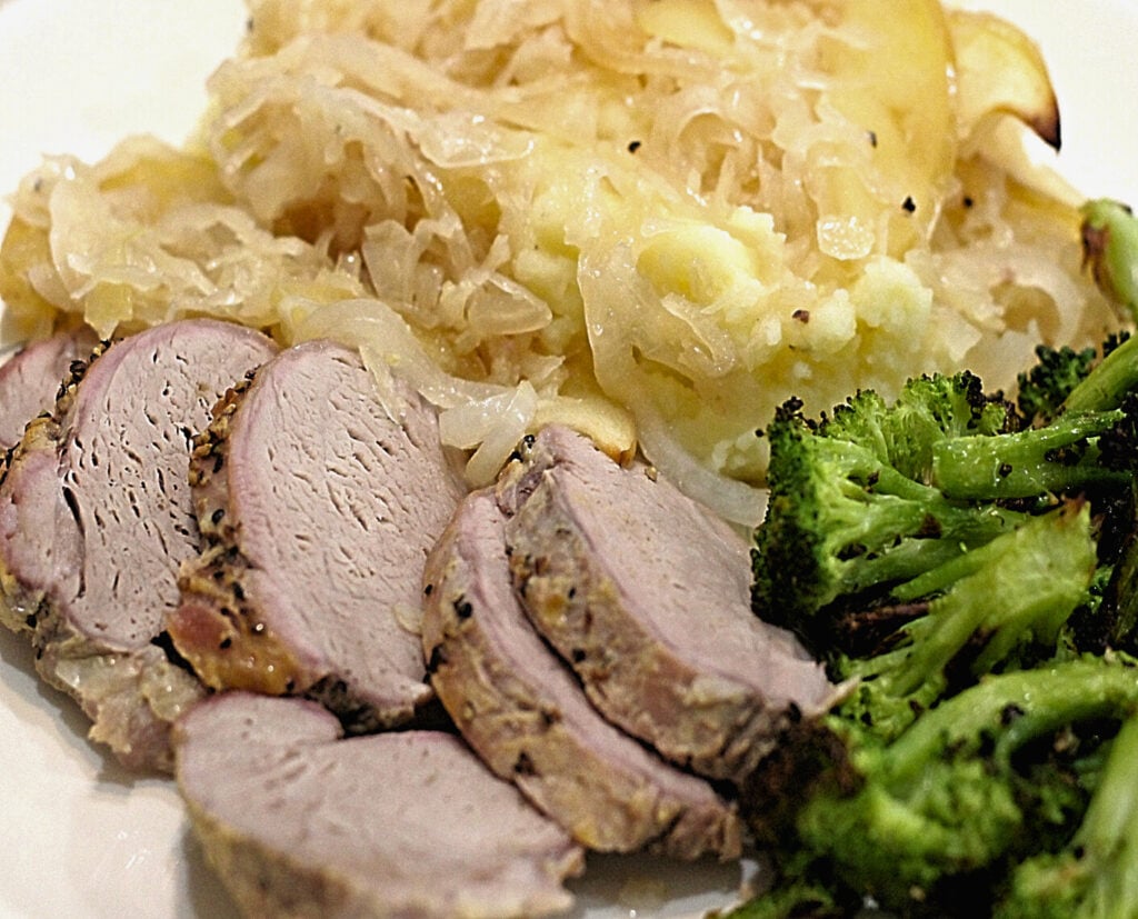 roast pork tenderloin with sauerkraut apples onions served over mashed potatoes and roasted broccoli