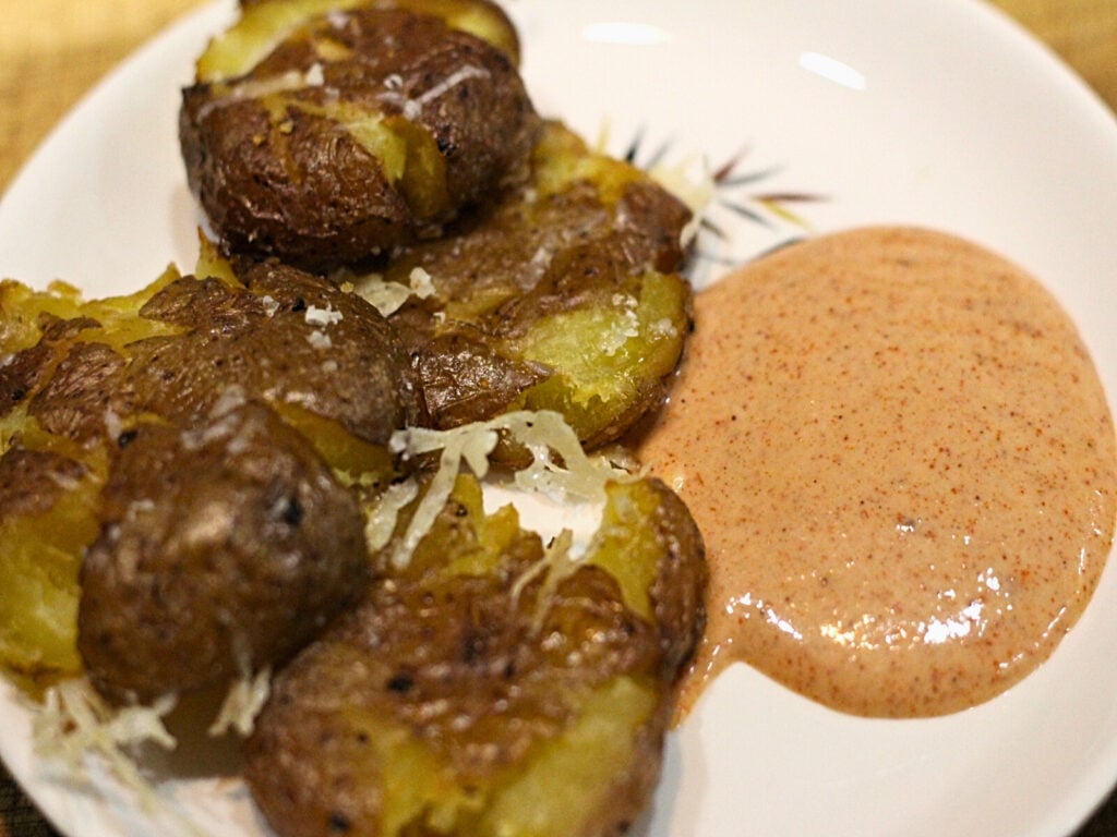 plate of crispy smashed potatoes with dipping sauce