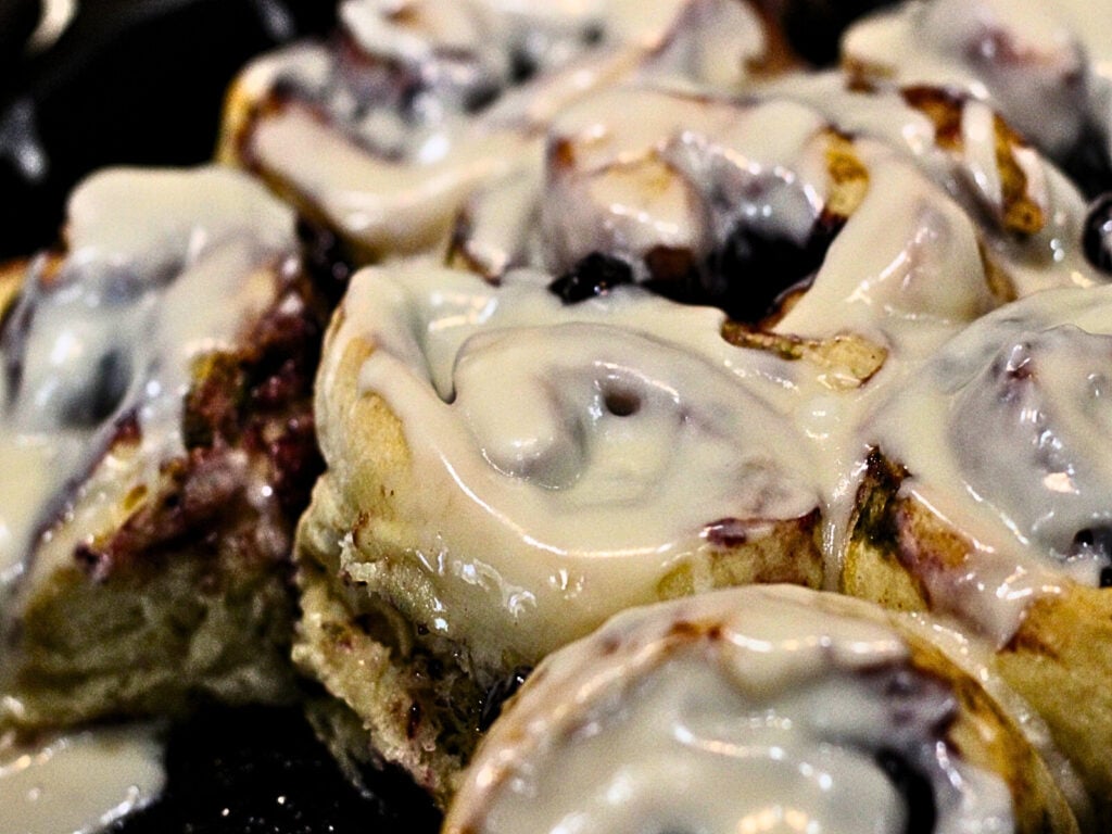 skillet of glazed sourdough blueberry cinnamon rolls